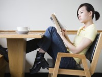 Young Woman Reading Book in Coffee Shop